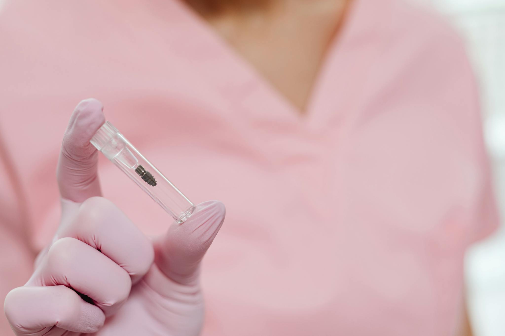 Close-up of a nurse holding a dental implant in a sterile environment.